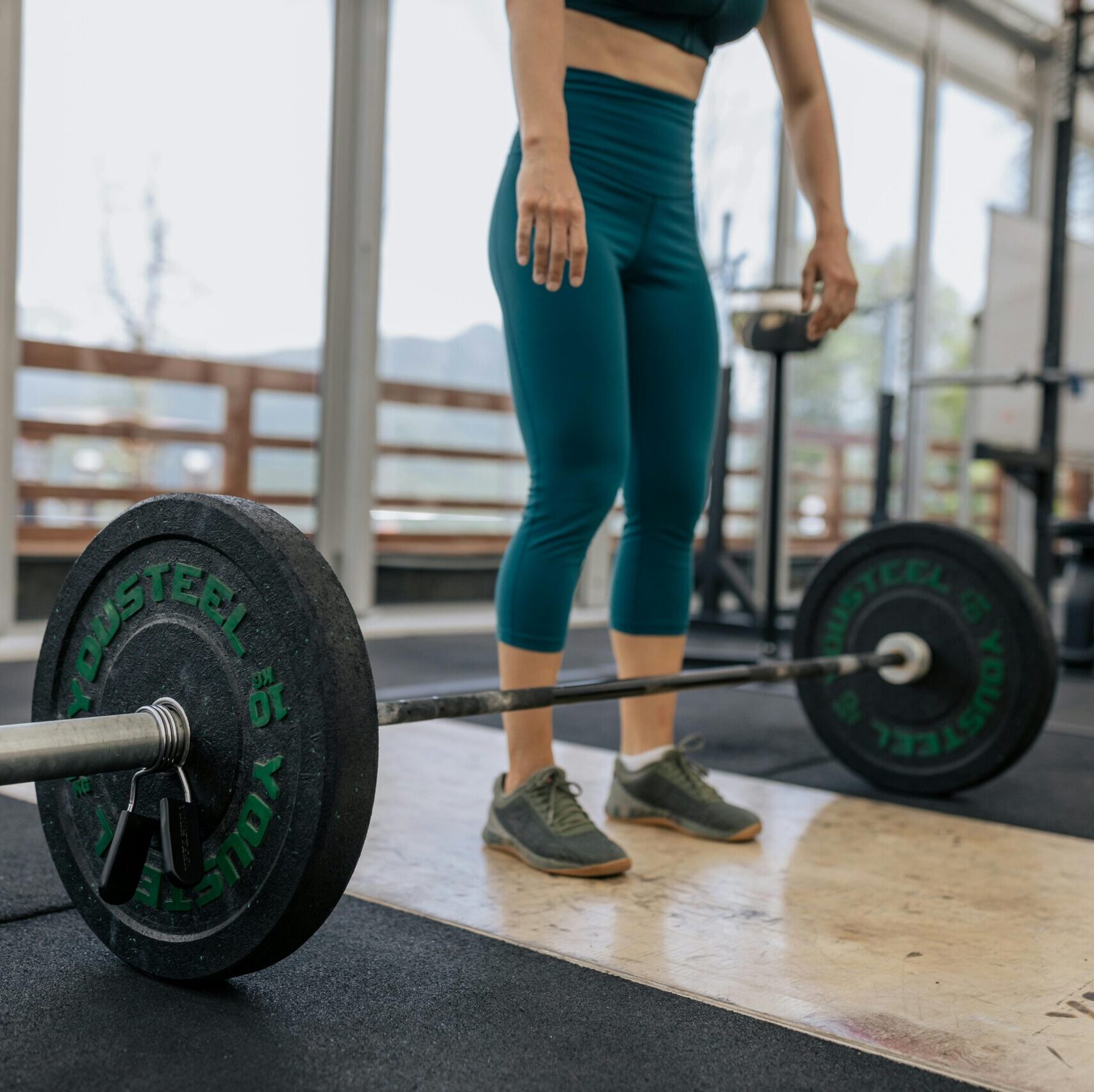 Female athlete preparing to lift a heavy barbell in a gym, showcasing fitness and strength.