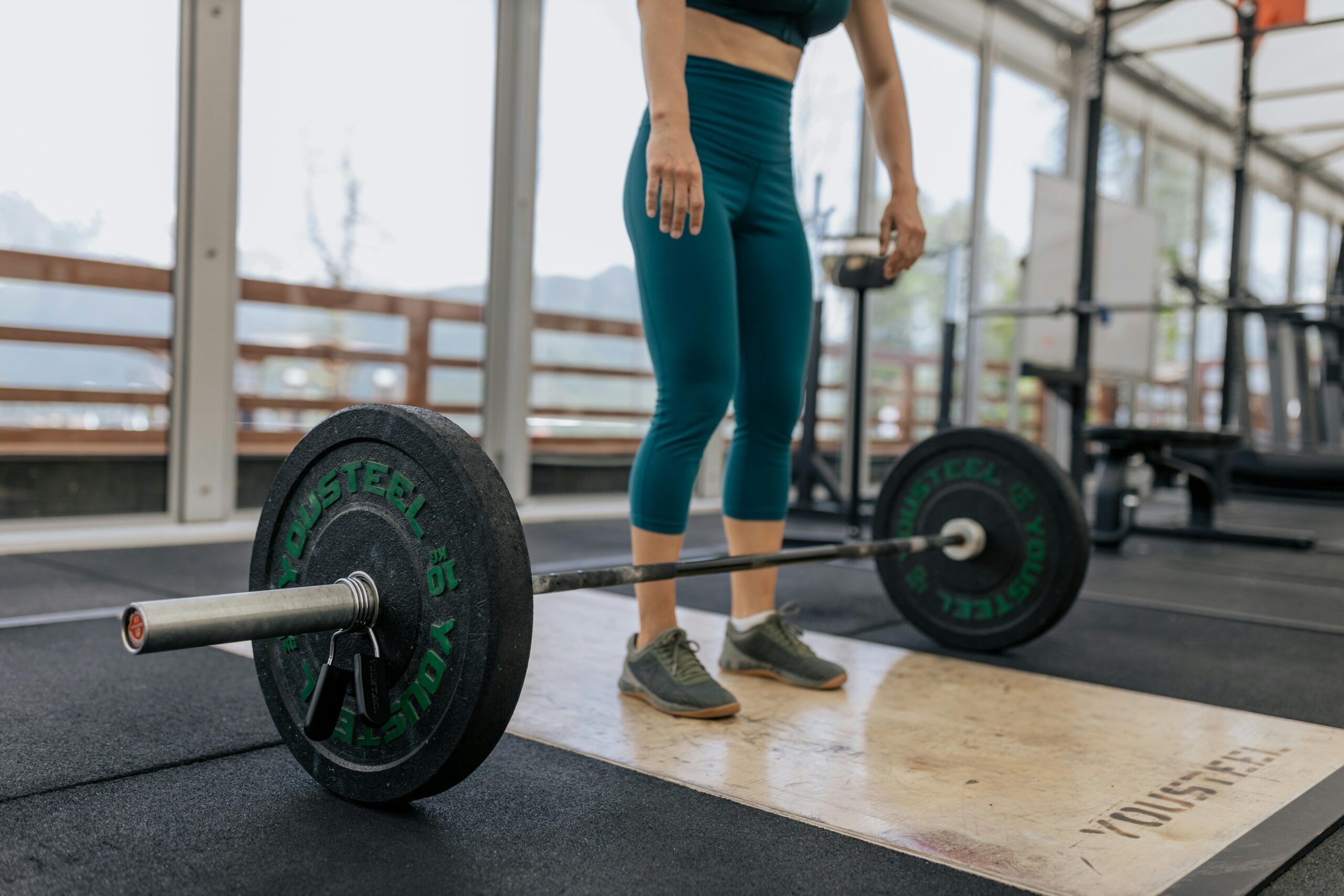 Female athlete preparing to lift a heavy barbell in a gym, showcasing fitness and strength.
